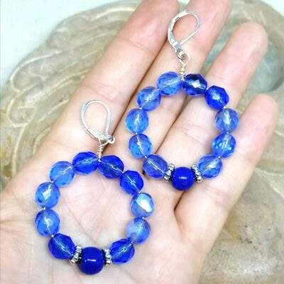 boucles d'oreilles en perles anciennes de Briare et perles en verre bleues posées dans une main