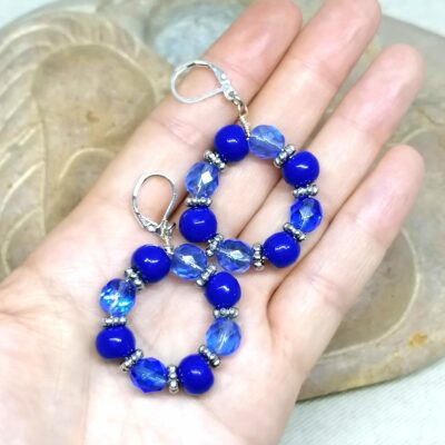 des boucles d'oreilles en perles anciennes bleues de Briare et en verre bleues sont posées dans une main