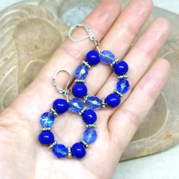 des boucles d'oreilles en perles anciennes bleues de Briare et en verre bleues sont posées dans une main