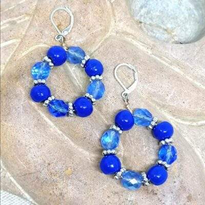 des boucles d'oreilles en perles bleues anciennes de Briare et en verre bleues sont posées sur une sculpture plate en pierre