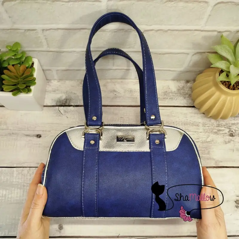 deux mains féminines montrent un sac rétro chic de couleur bleu et argenté effet miroir