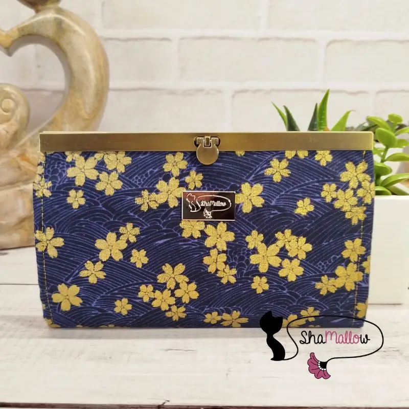 Découvrez le portefeuille compagnon bleu marine à fleurs de sakura dorées, 12 compartiments cartes et poche zippée monnaie. Création artisanale Shamallow.