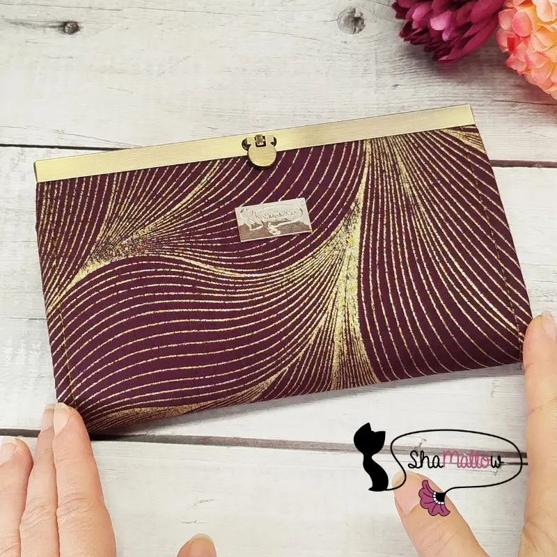 portefeuille compagnon en tissu wax prune avec vagues dorées et fermoir doré.